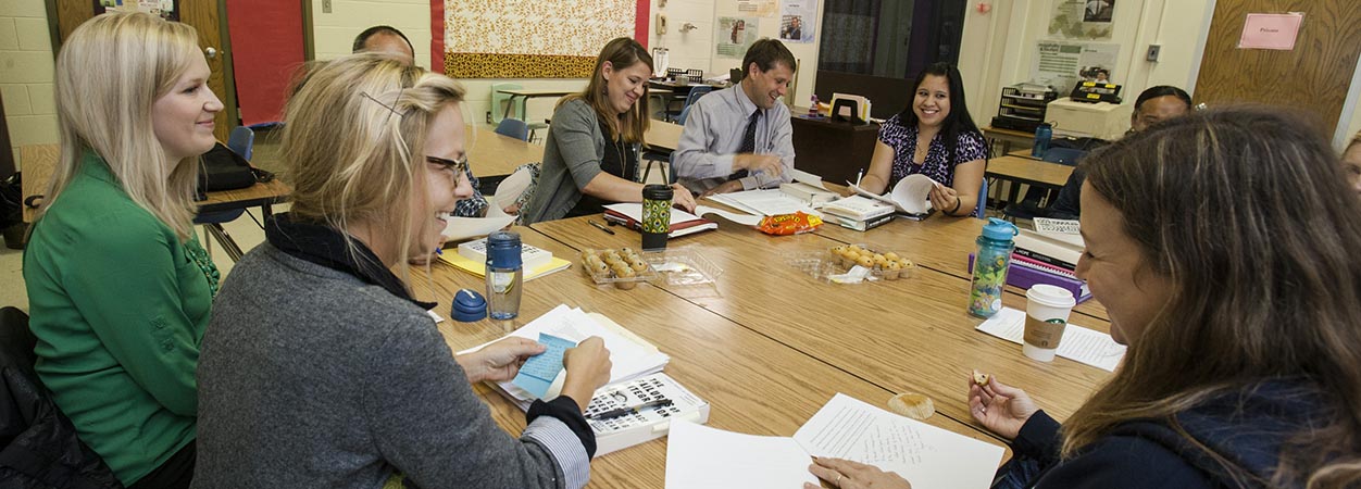 A group of teachers works together around a large table.