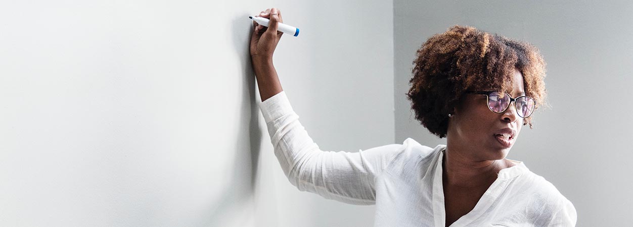 An adult teacher stands at a blank board.